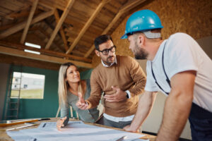 Young couple talking to construction worker about housing design plans at construction site