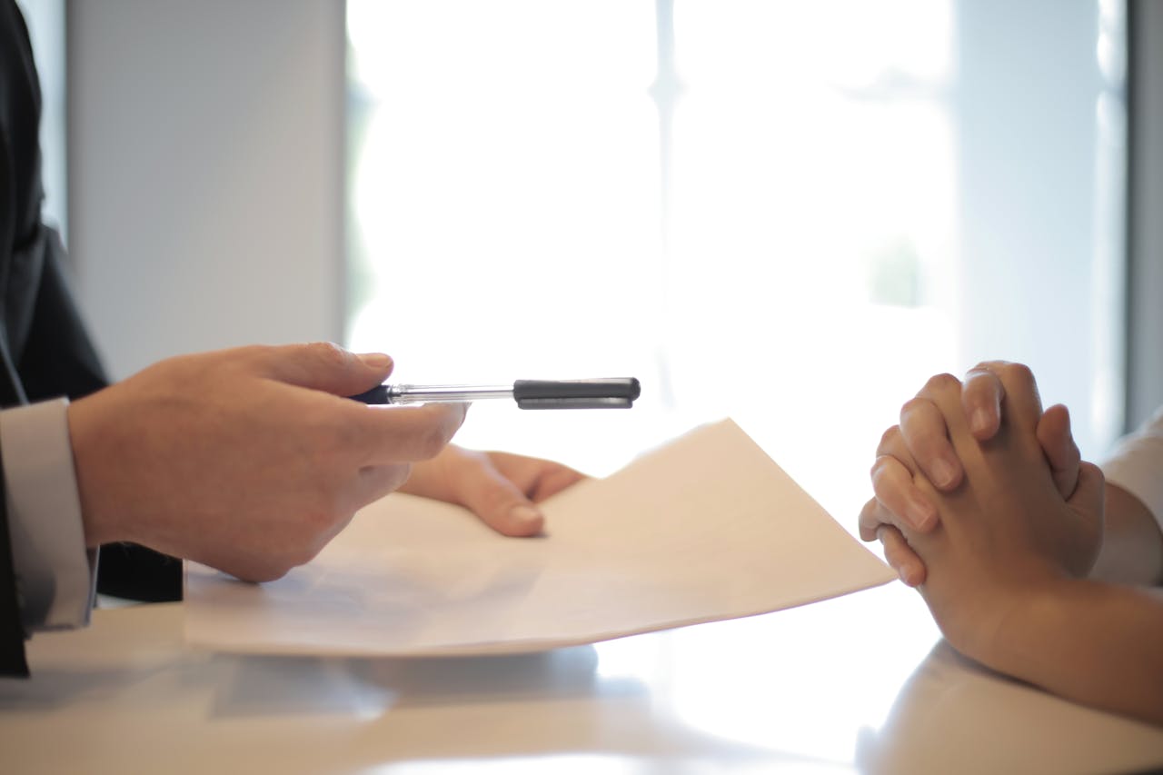 person holding pen and paper and person with hands crossed